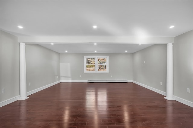 unfurnished room featuring dark hardwood / wood-style floors, a baseboard heating unit, and ornate columns