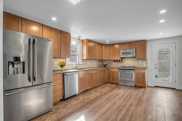 kitchen with light hardwood / wood-style floors, appliances with stainless steel finishes, sink, and decorative backsplash