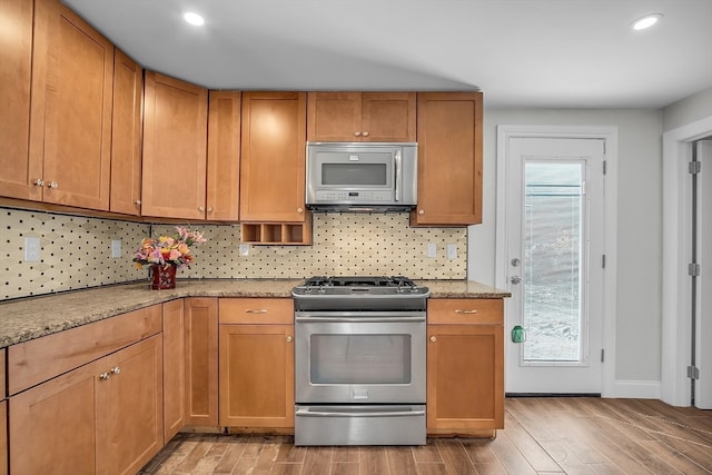 kitchen featuring decorative backsplash, light hardwood / wood-style flooring, light stone counters, and gas range