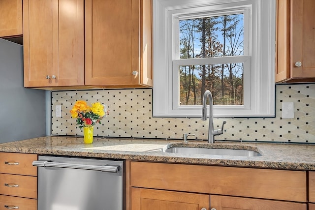 kitchen featuring light stone counters, decorative backsplash, sink, and stainless steel dishwasher