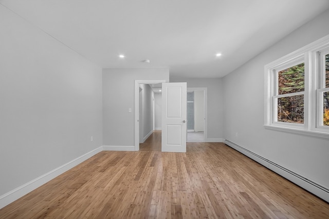 unfurnished bedroom with a baseboard heating unit and light wood-type flooring