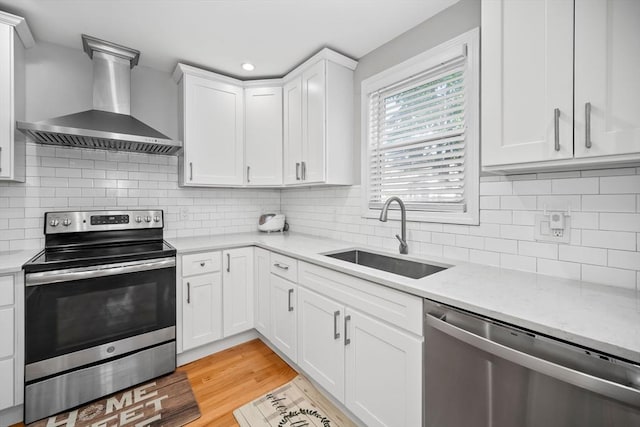 8 Nicholl St, Quincy, MA 02169 - kitchen featuring stainless steel appliances, wall chimney exhaust hood, white cabinetry, light stone countertops, and recessed lighting