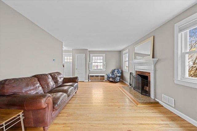 living room featuring visible vents, baseboards, wood finished floors, and a fireplace