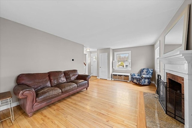 living area with hardwood / wood-style floors, baseboards, and a brick fireplace