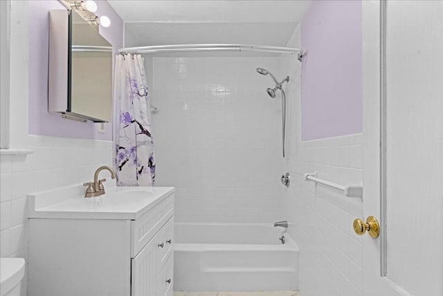 bathroom with shower / tub combo, vanity, toilet, wainscoting, and tile walls