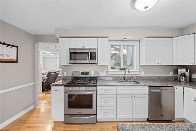 kitchen featuring light wood-style floors, a sink, white cabinetry, and stainless steel appliances