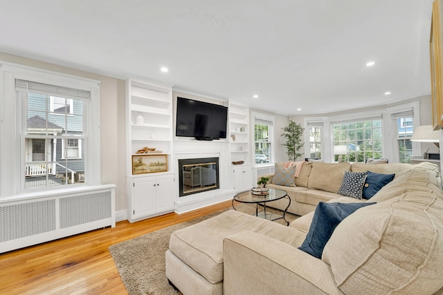 98 Haseltine St, Haverhill, MA 01835 - living room with radiator, a fireplace, light wood finished floors, recessed lighting, and crown molding