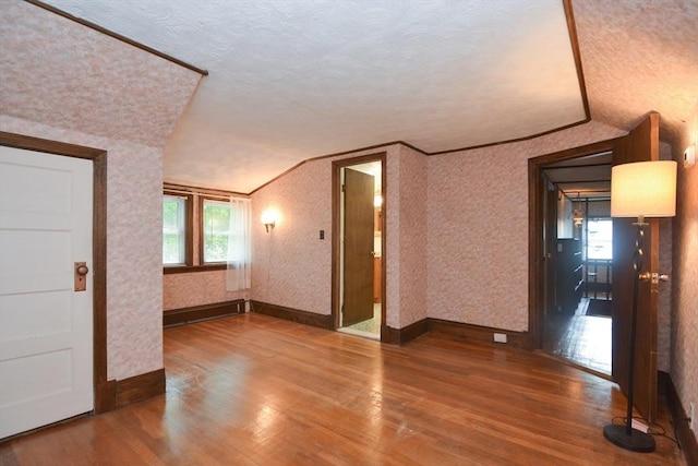 241 Fisher St, Walpole, MA 02081 - unfurnished room featuring wood finished floors, vaulted ceiling, a textured ceiling, wallpapered walls, and a baseboard heating unit