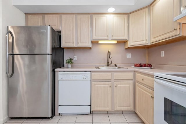 kitchen with white dishwasher, freestanding refrigerator, a sink, stove, and light countertops