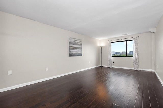 empty room featuring dark wood-style floors and baseboards