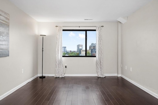 spare room featuring wood finished floors, baseboards, and a city view