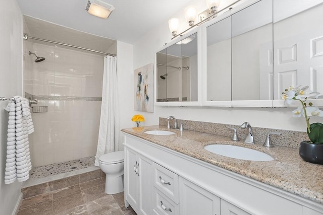 bathroom featuring tiled shower, toilet, and double vanity