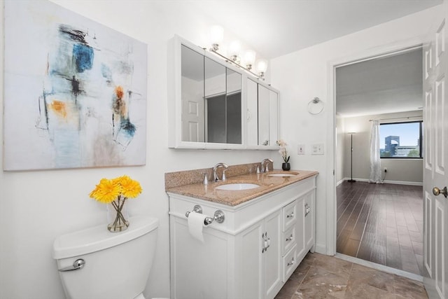 bathroom featuring double vanity, toilet, and baseboards