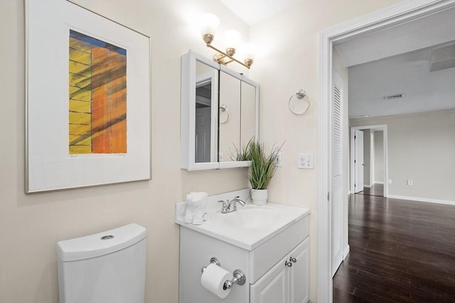 bathroom with wood finished floors, vanity, toilet, and baseboards