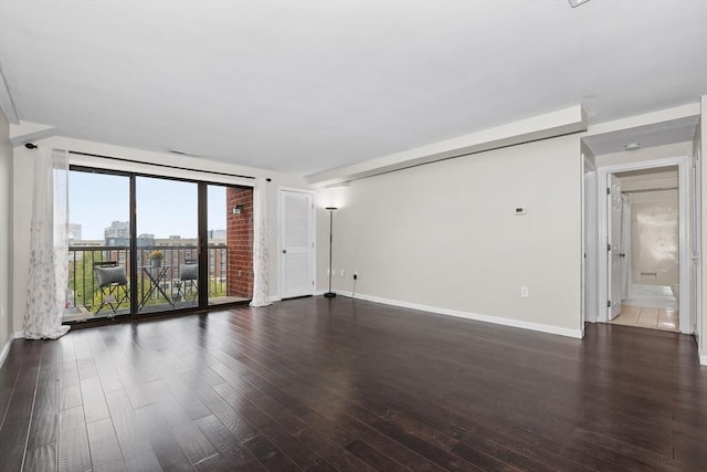 spare room featuring dark wood finished floors and baseboards