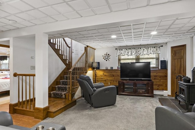 carpeted living room featuring a wood stove, stairway, recessed lighting, and a baseboard radiator