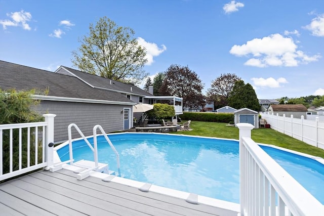 view of swimming pool featuring a storage unit, a deck, and an outbuilding