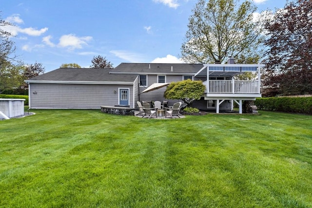 rear view of house featuring a deck, a chimney, a lawn, and a patio area
