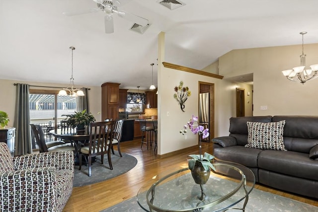 living room with a chandelier, lofted ceiling, light wood finished floors, and ceiling fan
