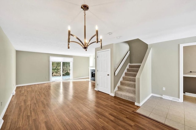 unfurnished living room with dark wood-style floors, stairs, baseboards, and a fireplace