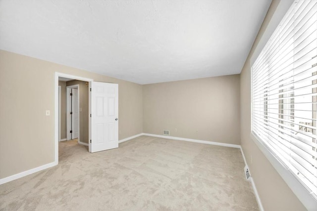 unfurnished room with light carpet, visible vents, and baseboards