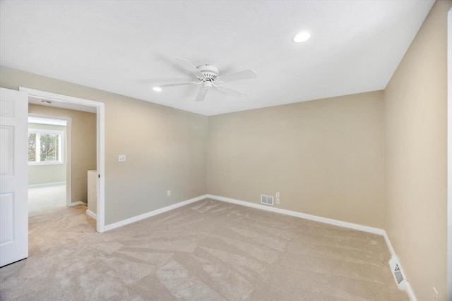 spare room featuring baseboards, visible vents, ceiling fan, and light colored carpet