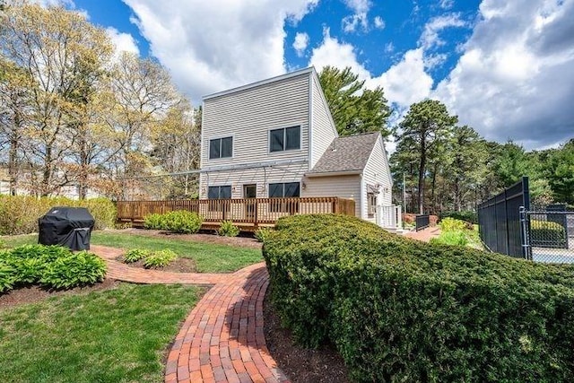 back of house with fence, a deck, and a lawn