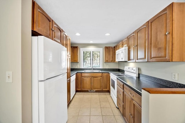 kitchen featuring brown cabinetry, dark countertops, white appliances, and light tile patterned flooring