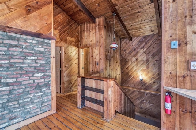 interior space with lofted ceiling with beams, wooden walls, an upstairs landing, wood ceiling, and wood-type flooring