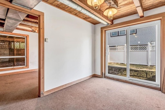 empty room featuring beam ceiling, carpet, wooden ceiling, and baseboards