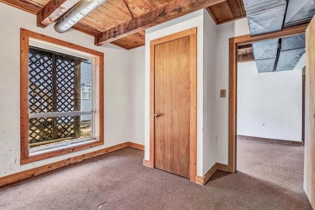 interior space with carpet floors, wood ceiling, beam ceiling, and baseboards