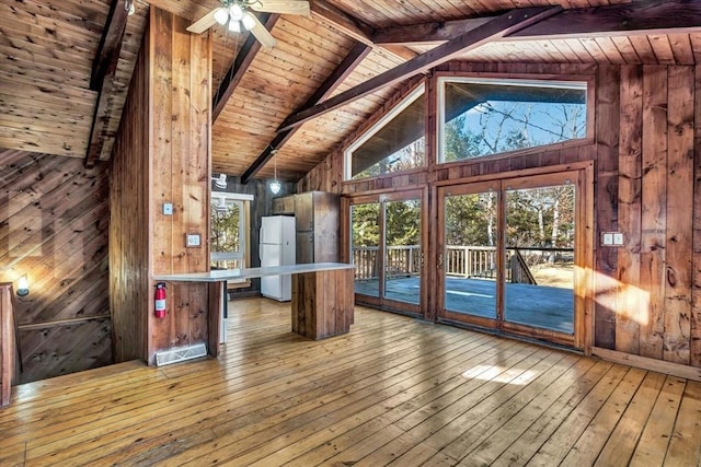 interior space featuring light wood finished floors, wooden walls, wood ceiling, ceiling fan, and beam ceiling