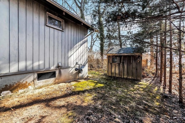 view of side of home with board and batten siding, an outdoor structure, and a storage unit