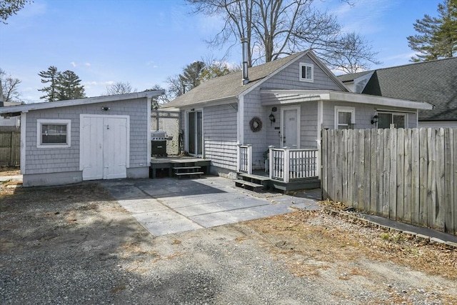 exterior space featuring an outbuilding, a patio, fence, driveway, and a deck