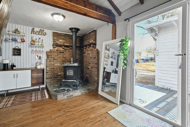 interior space featuring plenty of natural light, a textured ceiling, a wood stove, and wood finished floors