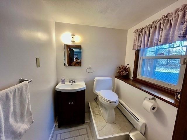 bathroom featuring vanity, toilet, and baseboard heating