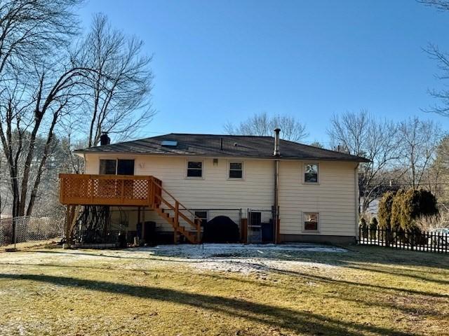 rear view of house featuring a wooden deck and a yard