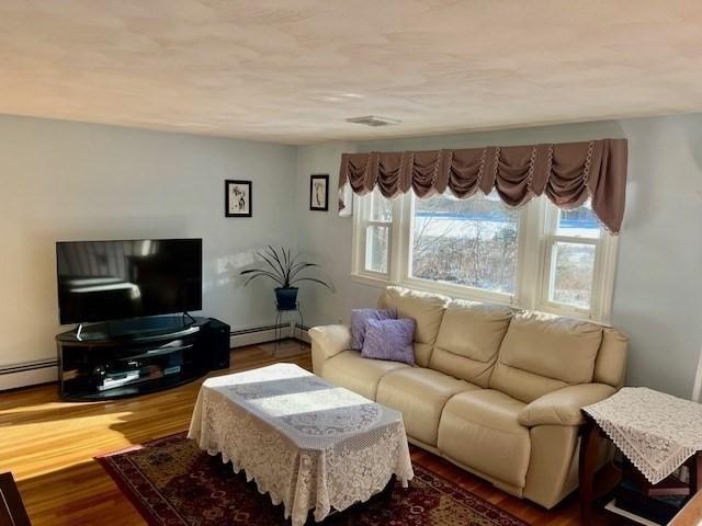 living room with hardwood / wood-style flooring and a baseboard heating unit