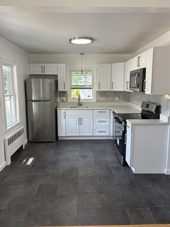 63 Bernice Ave, Brockton, MA 02301 - kitchen with appliances with stainless steel finishes, radiator heating unit, white cabinets, light countertops, and decorative backsplash