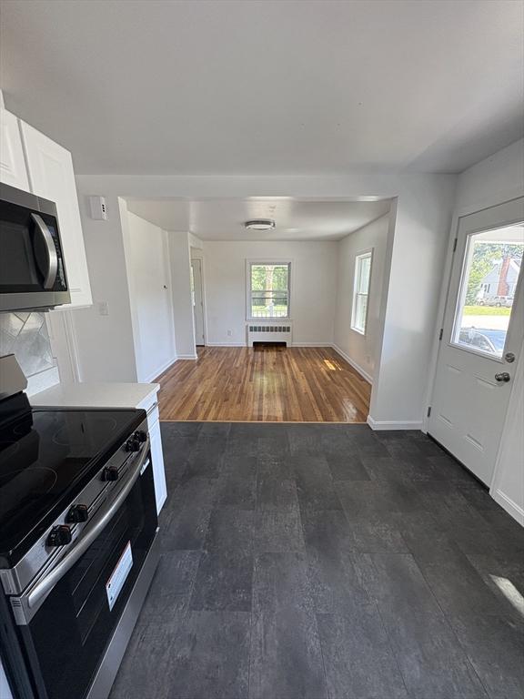 63 Bernice Ave, Brockton, MA 02301 - kitchen with appliances with stainless steel finishes, dark wood-type flooring, white cabinets, open floor plan, and radiator