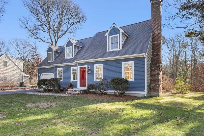 cape cod house with a front yard and a garage