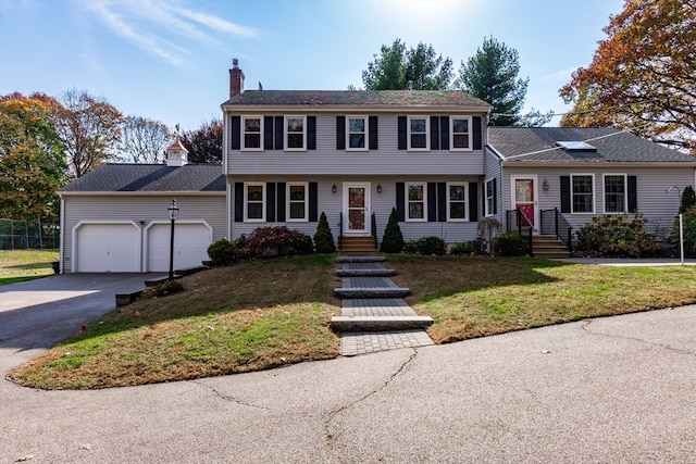 colonial-style house featuring a front yard and a garage