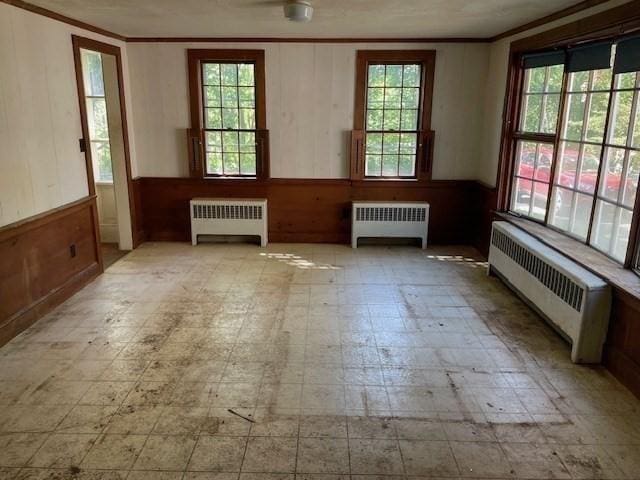 1 Pine Island Rd, Newbury, MA 01951 - empty room with radiator, tile patterned floors, crown molding, wood walls, and a wainscoted wall