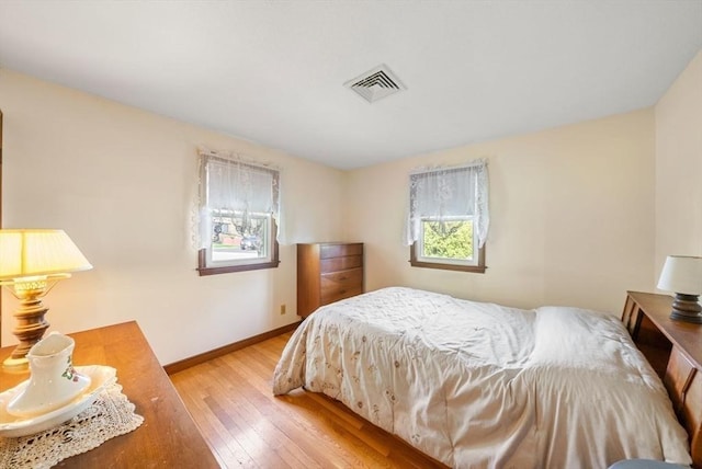 bedroom with baseboards, visible vents, and hardwood / wood-style flooring