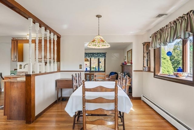 dining room with visible vents, baseboard heating, light wood finished floors, and a fireplace
