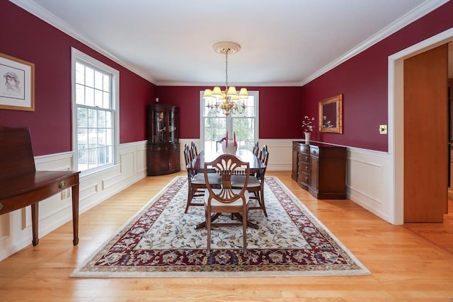 dining room featuring a healthy amount of sunlight, a wainscoted wall, light wood finished floors, and a chandelier