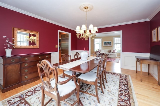 dining room featuring a chandelier, a wainscoted wall, light wood-style flooring, and crown molding