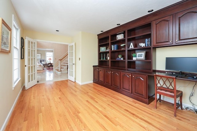 unfurnished office featuring light wood-type flooring, french doors, and baseboards