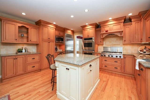 kitchen featuring built in appliances, light wood-style flooring, a center island, and ornamental molding