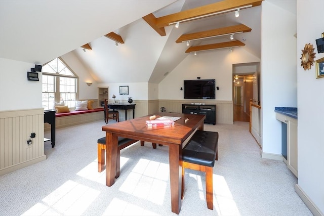 dining room with a wainscoted wall, light colored carpet, and vaulted ceiling with beams